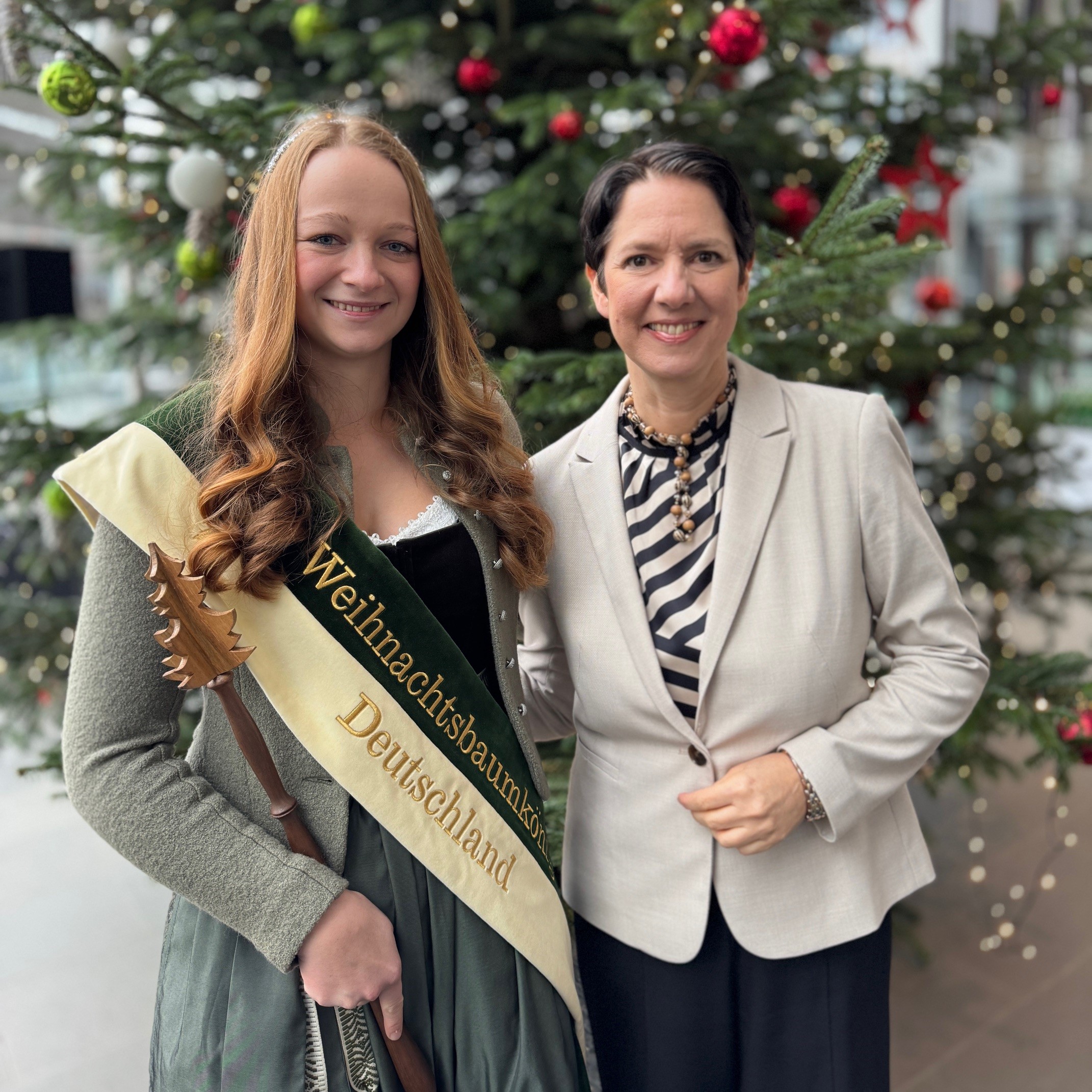 Die Ministerin steht neben der Weihnachtsbaumkönigin.
