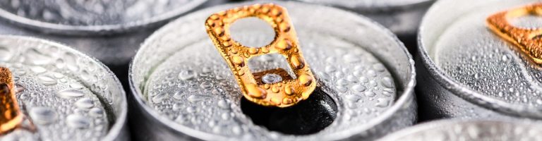 Eine offene Getränkedose steht neben geschlossenen Getränkedosen.