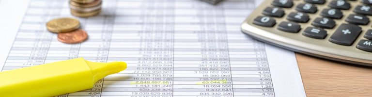 Auf einer Tabelle mit Zahlen liegt ein Textmarker und ein Taschenrechner.