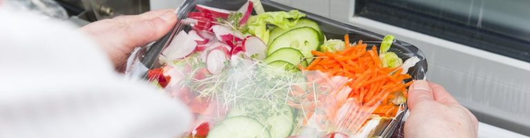 Ein Person verpackt einen Salat.