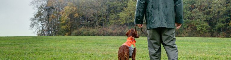 Ein Jäger spaziert mit seinem Hund.