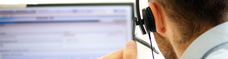 Ein Mann mit Headset guckt auf einen Monitor.